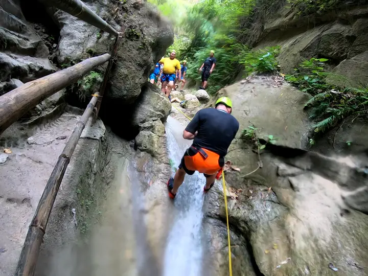 A group in helmets making their way down the narrow jungle canyon